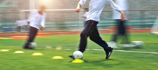 Low section of young boys playing soccer game with blurred motion