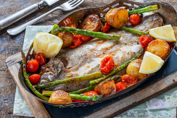 Lemon sole baked with potatoes, baby tomatoes and asparagus