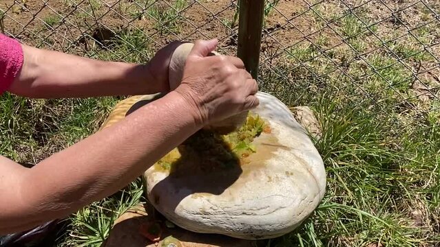 c&aacute;mara lenta de mujer peruana moliendo de manera tradicional rocoto en piedras (bat&aacute;n y chungo)