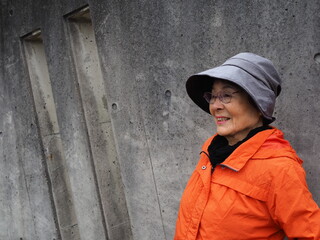 コンクリートの壁にもたれて微笑む高齢日本人女性