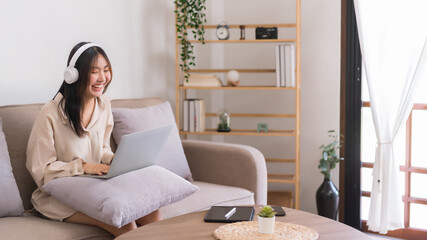 Concept of relaxation at home, Asian woman is laughing while sitting on sofa to watching movie
