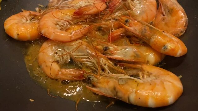 shrimps are fried in a frying pan with garlic