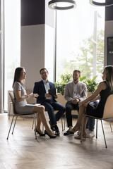 Group of smiling positive employees engaged in teambuilding, take part in morning briefing, laughing, joking enjoy friendly communication while solve business, discuss deal or project, feel satisfied