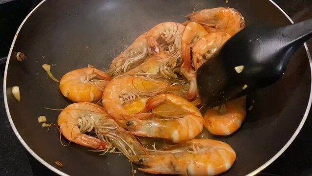 shrimps are fried in a frying pan with garlic