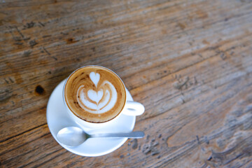 white cup of cappuccino on wooden background with beautiful latte art