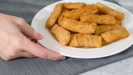 Fish sticks in a crunchy golden breading close-up on white plate