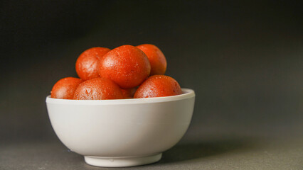 Sweet Gulab Jamun served in white bowl, Famous Indian dessert sweets isolated over black indoor studio background