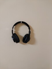 Fototapeta na wymiar Hanging wireless black headphones on the wall