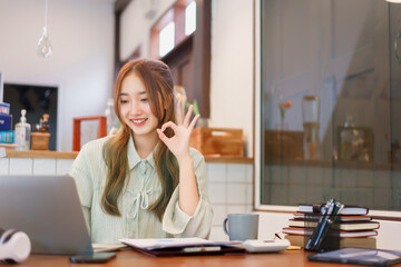 Coworking space office concept, Woman entrepreneur doing ok gesture while meeting on video call