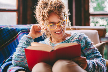 Serene people enjoying relax and indoor leisure activity at home reading a book with red cover....
