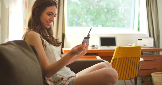 Woman, sofa and phone with credit card for online shopping, sale or discount on internet in home. Happy shopper girl, couch and ecommerce with digital store, smartphone and e commerce app in Miami