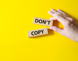 Don't copy symbol. Wooden blocks with words Don't copy. Beautiful yellow background. Businessman hand. Business and Don't copy concept. Copy space.