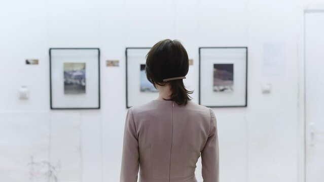 View from the back. Young woman in an art gallery