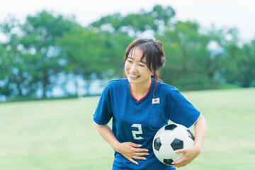 趣味でサッカー・フットサルの練習をしながら爆笑する日本人女性
