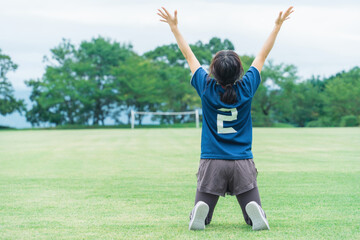 Obraz premium サッカー場でフットサル・サッカーで勝利して喜ぶサッカー選手の女性 