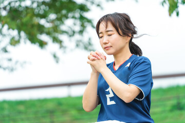 Fototapeta premium 祈るように日本代表を応援するサッカーファン・サポーターの日本人女性 