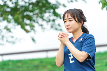 祈るように日本代表を応援するサッカーファン・サポーターの日本人女性
