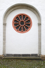 Romanischer Rundbogen mit Rosettenfenster an der Außenseite der Pfarrkirche St. Servatius in...