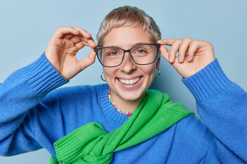 Portrait of short haired female student geek wears big transparent eyeglasses for good vision...