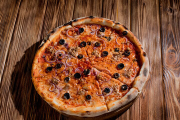 Pizza with tuna, olives, onions, mozzarella cheese and tomato sauce on wood background. Top view, copy space