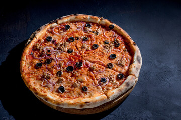 Pizza with tuna, olives, onions, mozzarella cheese and tomato sauce on a black background. Top view