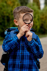 Schoolboy looking through a magnifying glass, with a surprised expression, squinting his eyes