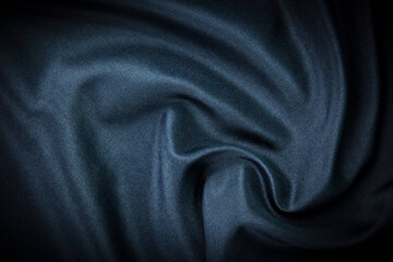 A dark modern satin texture wallpaper and background. Luxury smooth blue silk and satin fabric concepts.