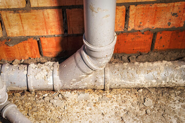 Sewer pipes in home basement. System of gray sanitary pipes when building a house. Sewer...