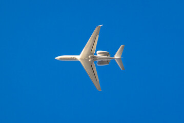 White private jet against blue sky traveling  west