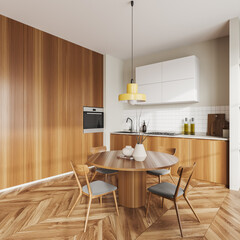 Light kitchen interior with dining table and cooking corner. Empty wall