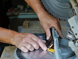 working with a miter saw in a carpenter's workshop, close-up, cutting a wooden fillet on a circular...