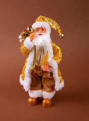 A funny Santa Claus toy with a bag of gifts on its back and a Christmas tree in its hand and golden pants.