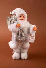 A funny Santa Claus toy with a bag of gifts on its back and a Christmas tree in its hand and white pants.