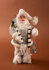 A funny Santa Claus toy with a bag of gifts on its back and a Christmas tree in its hand and white pants.