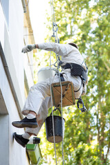 male climber builder paints the facade of the building