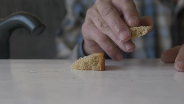 close-up a piece of bread from the table takes the hands of an elderly man with a walking stick. the theme of the need for old age, world crisis, bread shortage, hungry old age