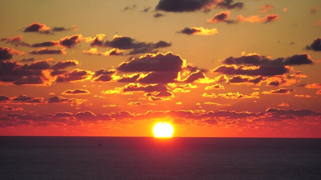 Timelapse. A red burning sunset over the sea. Abstract nature summer or spring ocean sea background. Small waves on golden warm water surface with bokeh lights from sun.