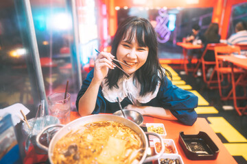 Young adult southeast asian woman holding chopsticks for Korean hot pot meal lifestyle with traditional street food