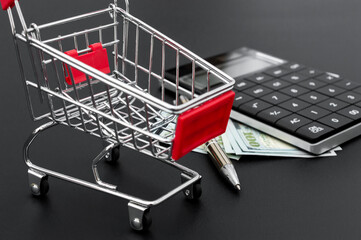Shopping cart with calculator and money. Business concept.