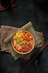 Mee Siam Singapore is a dish of thin rice vermicelli with sour soup on dark background taken with flatlay angle