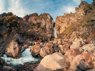 Scenic autumn landscape with vertical big Sultan waterfall at mountain top in sunshine in the Jila-Su tract. Kabardino-Balkaria. Russia, Caucasus. High falling water in Northern Elbrus region.
