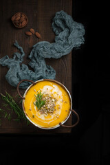 a pumpkin soup on edge dark rustic wood table,taken from flatlay angle