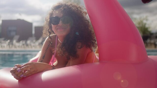 Summer vacation plus size model woman in bikini on inflatable donut mattress in swimming pool. Hispanic girl student relaxing sunbathing enjoying travel holidays at resort pool.
