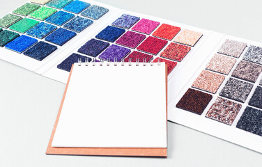Multicolored carpet swatches catalogue book and notepad on blue desk background. Interior or...