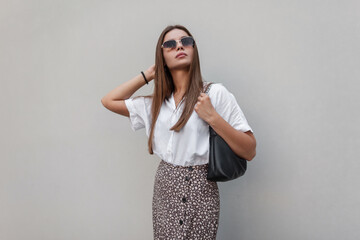 Fashionable beautiful summer woman model with vintage sunglasses in fashion clothes with a white...