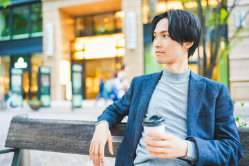ベンチに座ってコーヒーを飲む男性