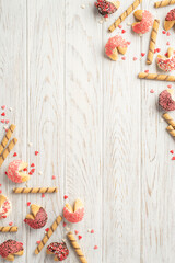 Valentine's Day concept. Top view vertical photo of confectionery heart shaped candies and cookies on white wooden desk background with empty space