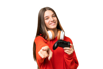 Teenager caucasian girl playing with a video game controller over isolated background pointing front with happy expression