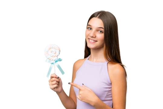Teenager caucasian girl holding a lollipop over isolated background and pointing it - Powered by Adobe