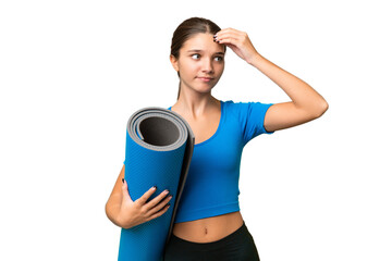 Teenager caucasian girl going to yoga classes while holding a mat over isolated background having...